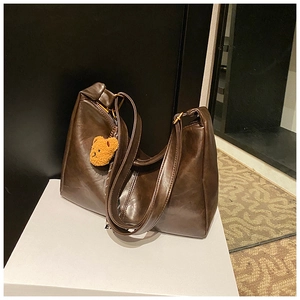 Detail of dark brown hobo bag in polished leather with a cute plush bear charm