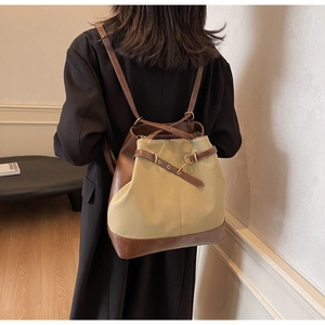 Detail of a vintage khaki and brown contrast stitching backpack with gold hardware buckles