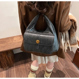 Dettaglio dello zaino vintage in pelle grigio scuro con fibbia dorata logo N sulla tasca