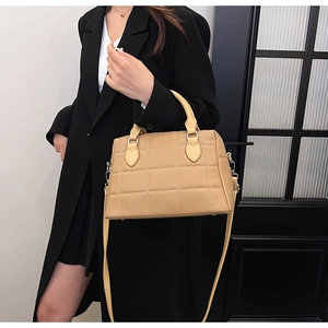 Detail of light brown quilted Boston bag with leather texture and top handles