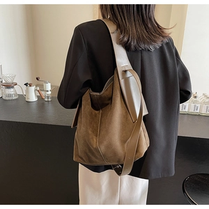 Macro detail of brown suede tote bag featuring fine stitching and metal buckle strap