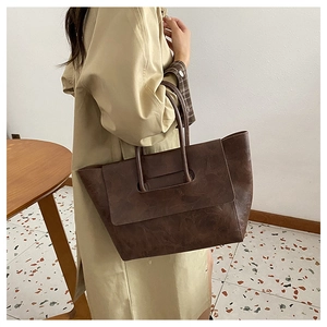 Detail of deep brown large tote bag with retro matte leather and unique handle design