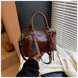 Détail du sac Boston en cuir ciré marron foncé avec finitions argentées et pompon tressé
