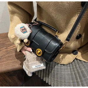 Détail du sac cylindre noir vintage avec fermoir doré et breloque en peluche