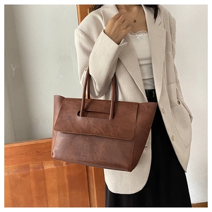 Close-up of vintage brown leather tote bag with unique flap-through handle detail