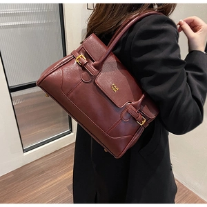 Detail of burgundy leather shoulder bag with gold logo buckle and long handle