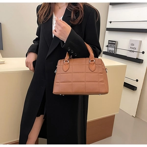 Brown quilted leather tote bag with top handles shown on model wearing a black coat