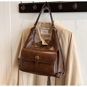 Dettaglio della borsa vintage in ecopelle marrone scuro con fibbia su un trench