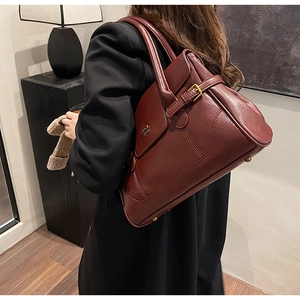 Detail of dark red leather tote bag with gold metal buckle and textured finish