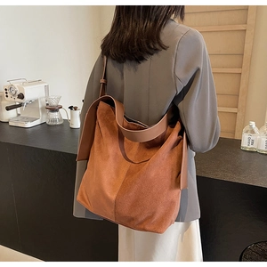 Detailed view of brown suede large hobo bag with wide leather strap on shoulder