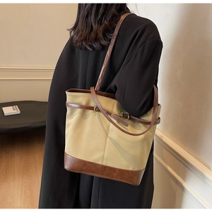 Detail shot of khaki canvas tote with brown leather trim and metal lock closure