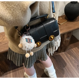 Détail du sac polochon noir rétro avec boucles dorées et breloque en peluche mouton