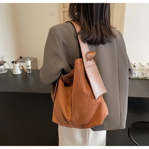 Detail of caramel suede hobo bag with wide shoulder strap and decorative knot details