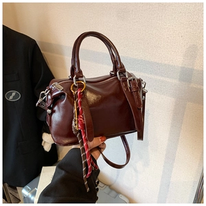 Détail du sac à main Boston bordeaux, finition brillante, poignées et breloque en corde