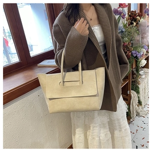 Detail of a beige vintage leather tote bag shown with a stylish Korean outfit