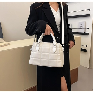 White quilted shell tote bag with adjustable strap worn by a model in a black blazer