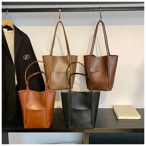 Detail view of four leather bucket tote bags in assorted autumn colors with slim straps