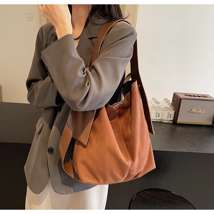 Close-up of a vintage brown suede tote bag featuring a wide strap and soft matte texture