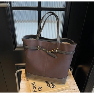 Detail of vintage brown and charcoal tote bag with golden metal hardware and buckle decor