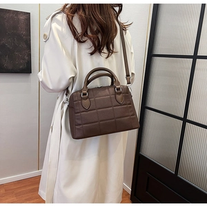 Detail view of dark brown quilted leather tote bag worn by model in trench coat
