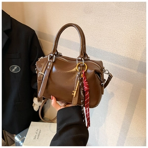 Détail du sac Boston marron vintage avec pendentif doré et pompons tressés