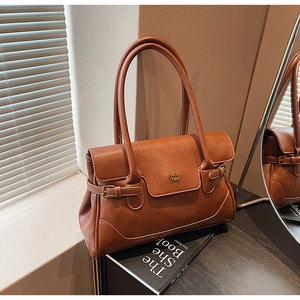 Detail of caramel brown faux leather handbag with FAN TOR metal logo and buckles