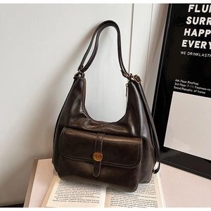 Dettaglio della borsa Hobo marrone scuro in PU con fibbia logo N su un espositore di libri