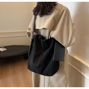 Detail view of a black large capacity tote bag worn with a stylish trench coat