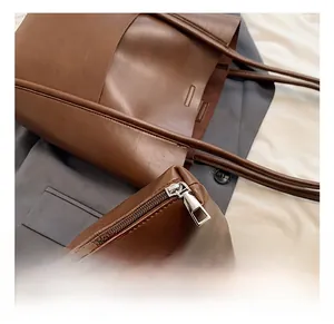 Detail showing the silver metal zipper and fine leather texture of the brown bucket bag