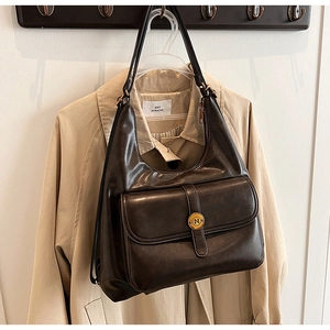 Dettaglio borsa hobo vintage in pelle marrone con fibbia dorata e logo 'N' inciso