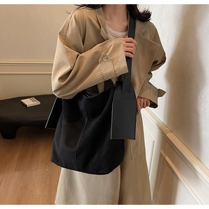 Minimalist black oversized tote bag with thick strap paired with a khaki trench coat
