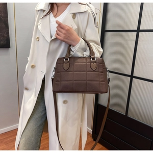 Quilted dark brown tote bag shown with a white trench coat and jeans on a model