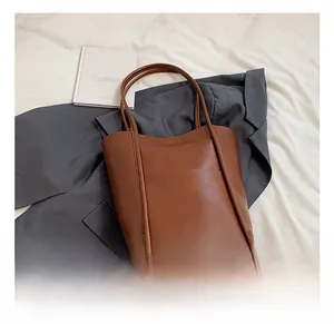 Detail showing the brown faux leather tote bag with vertical stitching and matte finish