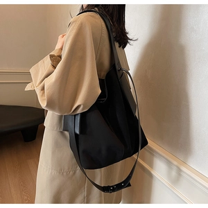 Close-up of black high-capacity tote bag showing nylon texture and leather strap on model