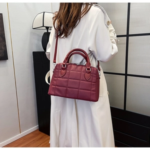 Close-up of wine red quilted leather tote bag worn with a casual trench coat
