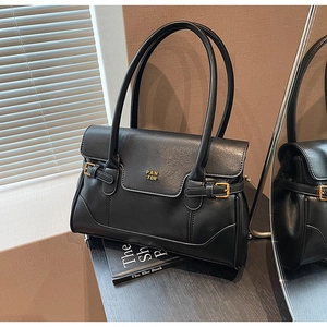 Detail of black glossy shoulder bag featuring golden logo and elegant buckle hardware