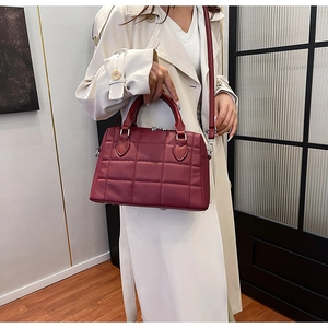 Fashionable burgundy quilted tote bag with cross-body strap shown in a lifestyle model setting