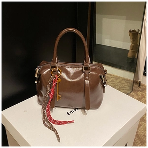 Détail du sac Boston marron brillant avec breloque clé et cordon tressé déco