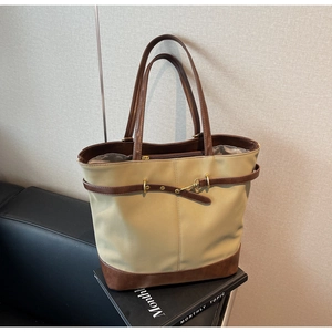 Detail view of the stitching and metal buckle on this large khaki canvas tote bag