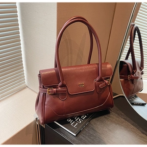 Detail of retro burgundy leather shoulder bag with metallic logo and adjustable buckle