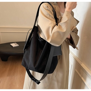 Detail view of the large black suede tote bag with adjustable wide leather strap on a model