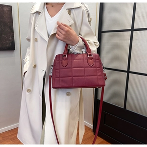 Detail of burgundy shell tote bag featuring quilted leather texture and dual top handles