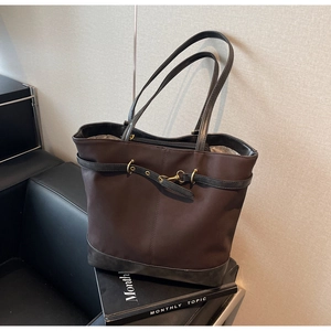 Detail of dark brown tote bag with vintage metal buckle and black leather strap stitching