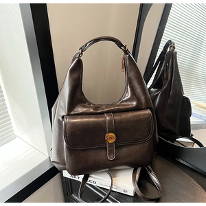 Dettaglio zaino vintage in pelle marrone con fibbia in metallo su un libro Art Deco