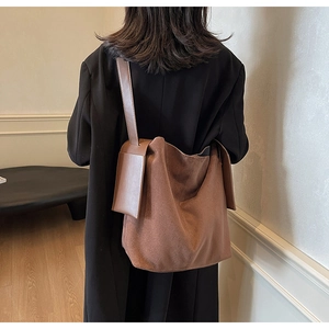 Close-up of premium brown suede bucket bag with wide shoulder strap for autumn style