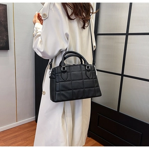Close-up of black quilted leather tote bag featuring lychee texture and silver hardware