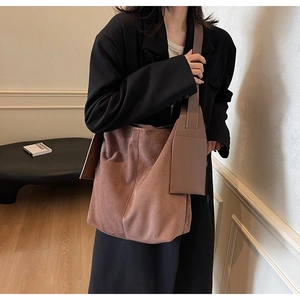 Close-up of a large brown suede tote bag with wide shoulder strap and mini pouch