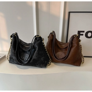 Détail de cabas vintage en cuir noir et marron avec chaînes métalliques et logo M