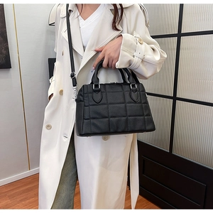Detail of black pebbled leather tote featuring classic square quilted pattern and top handle