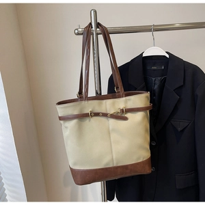 Detail of vintage tote bag with beige canvas, brown leather straps, and metal buckle